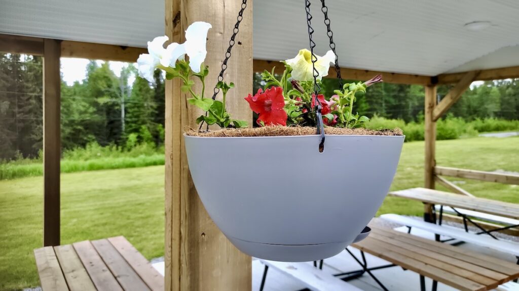 Community volunteers hang flower planters at the Dyment Recreation Hall pavilion in Melgund Township.