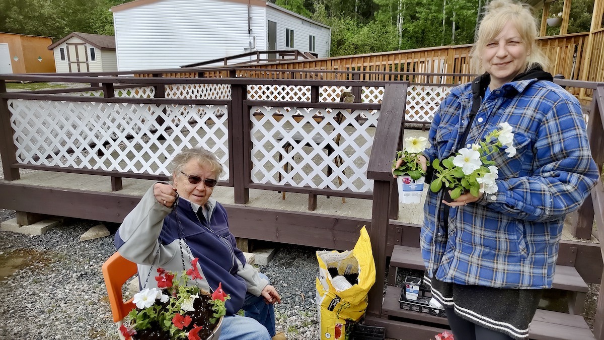 Terri Bell and Karen Daignault were among the community volunteers helping beautify Dyment Recreation Hall through flower planting, hanging planters, and community garden improvements.