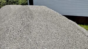 The first sign of progress! Piles of crushed gravel sit ready beside the Dyment Rec Hall, waiting to be laid down as sturdy concrete pads that will support accessible entrances and a new garden shed for the community garden.