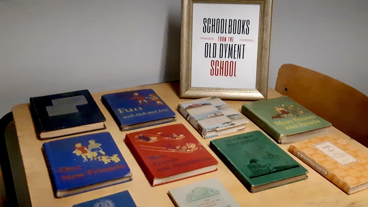 Classic titles like Fun with Dick and Jane and More Streets and Roads rest on a wooden desk, offering a personal glimpse into Northwestern Ontario classroom life from decades past.
