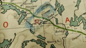A close-up view reveals local township names like Dyment, Taché, and Revell clearly marked alongside elevation contours and early railway lines. Pencil marks and faint blue shading highlight how past teachers or students actively engaged with the map during geography lessons.