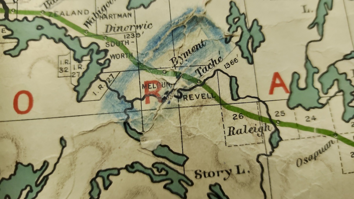 A close-up view reveals local township names like Dyment, Taché, and Revell clearly marked alongside elevation contours and early railway lines. Pencil marks and faint blue shading highlight how past teachers or students actively engaged with the map during geography lessons.