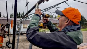 Armed with power tools and determination, Melgund LSB Chair Pat Daignault unfastens metal framing while dismantling the event tents at Dyment Park.